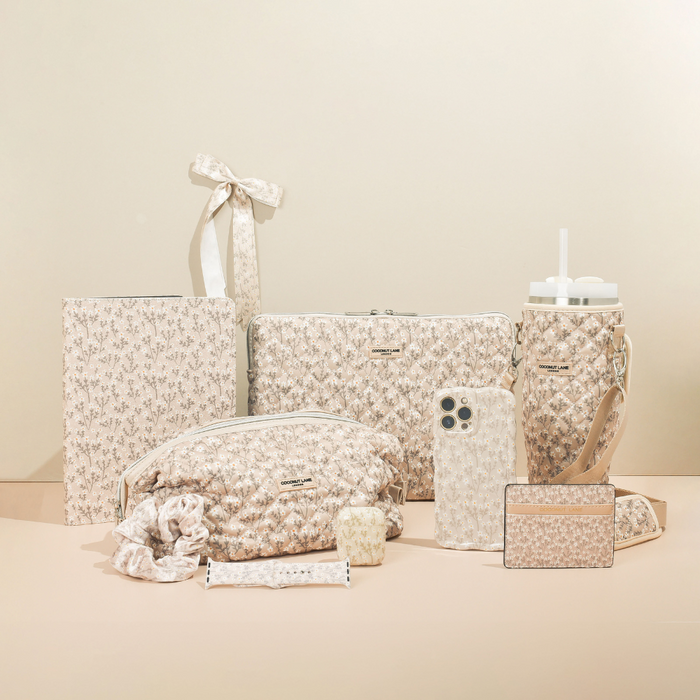 Nude floral Coconut Lane AirPods case with beige flower pattern, shown alongside matching accessories on a neutral background.