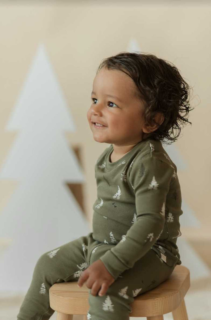 Baby boy wearing Petit Lem Conifer print pajamas in Forest Green organic cotton rib.