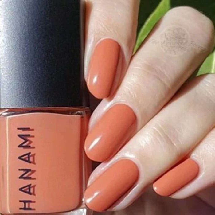 Hand with peach-coloured nails holding a bottle of Hanami nail polish.
