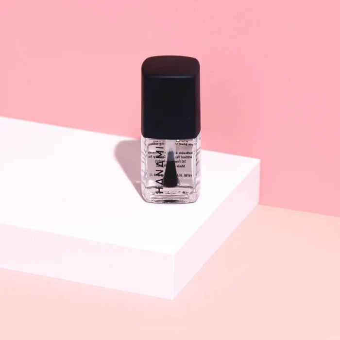 Nail polish bottle with black cap on a pink and white background.