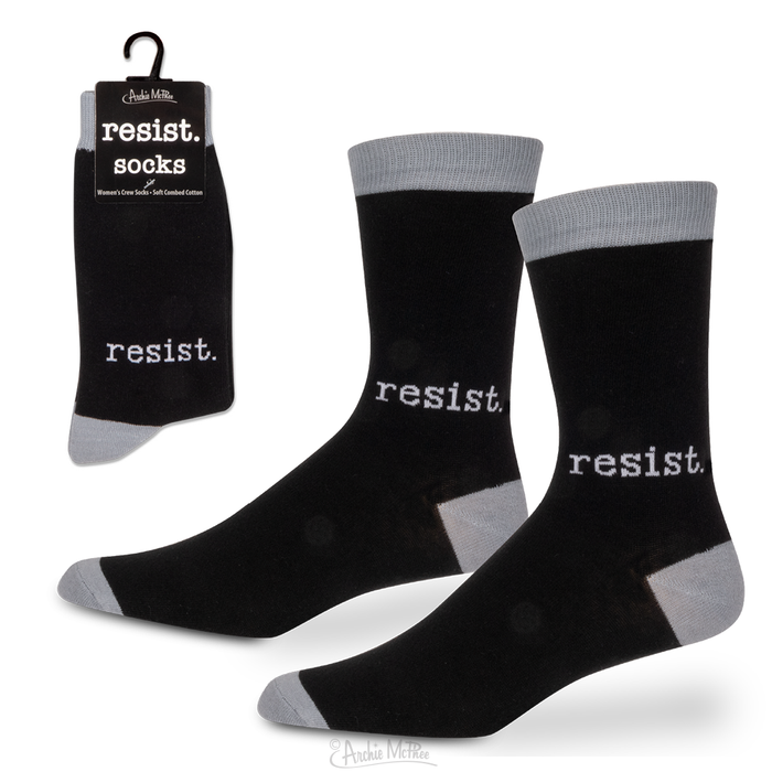 The Resist Socks for women display the word "resist" prominently in bold white text against a black background, complete with gray toes and cuffs. Crafted from a soft combed cotton blend, they are available both unpackaged and packaged, highlighting their stylish design.