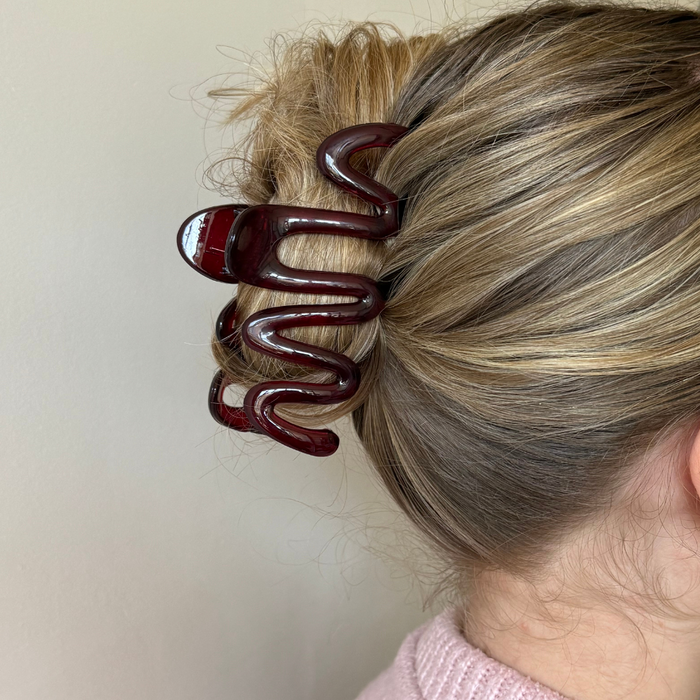 Burgundy squiggle-shaped claw clip securing blonde hair in an updo.