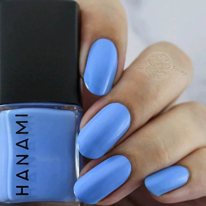Hand with blue nail polish holding a bottle of HANAMI nail polish.