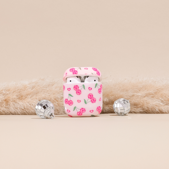 Coconut Lane Disco Cherries AirPods case with wireless earbuds, cherry pattern, and disco balls on beige background.