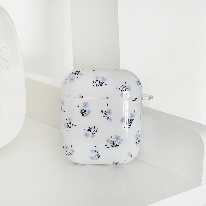 Coconut Lane AirPods case in periwinkle with blue and pink floral pattern, displayed on a white shelf against a white background.