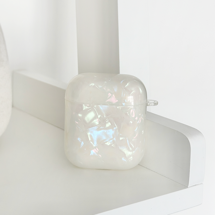 Coconut Lane Iridescent Pearl Airpods Case with a glossy finish on a white shelf in minimal decor.