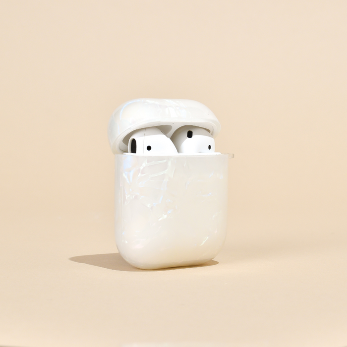 White wireless earbuds in an iridescent pearl Coconut Lane AirPods case on a beige background.