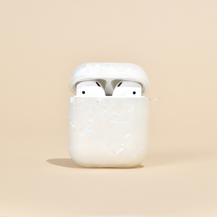 Iridescent pearl Coconut Lane Airpods case with white earbuds, open on a soft beige background.