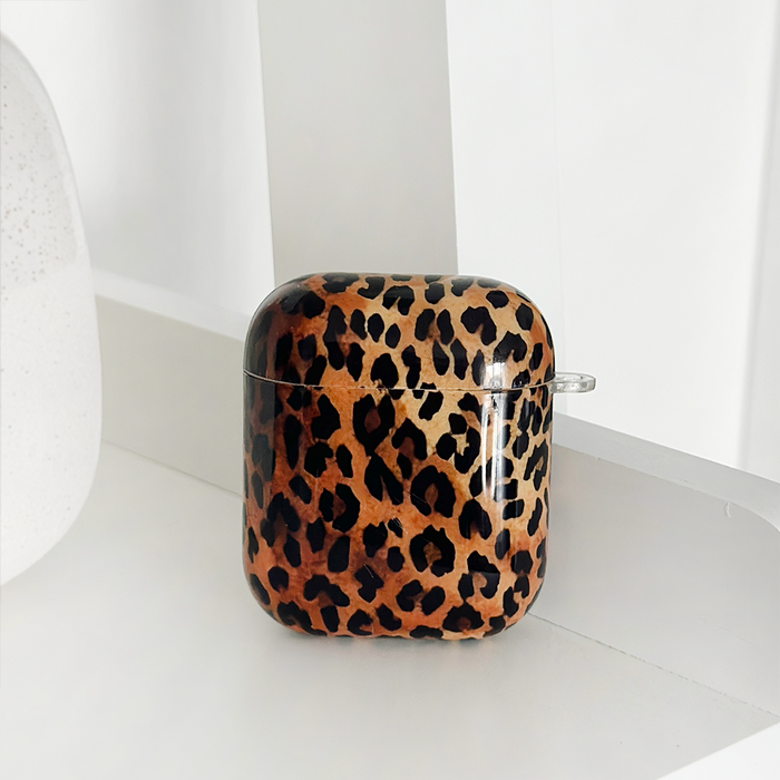 White AirPods case with brown and black leopard spots, Coconut Lane branding.