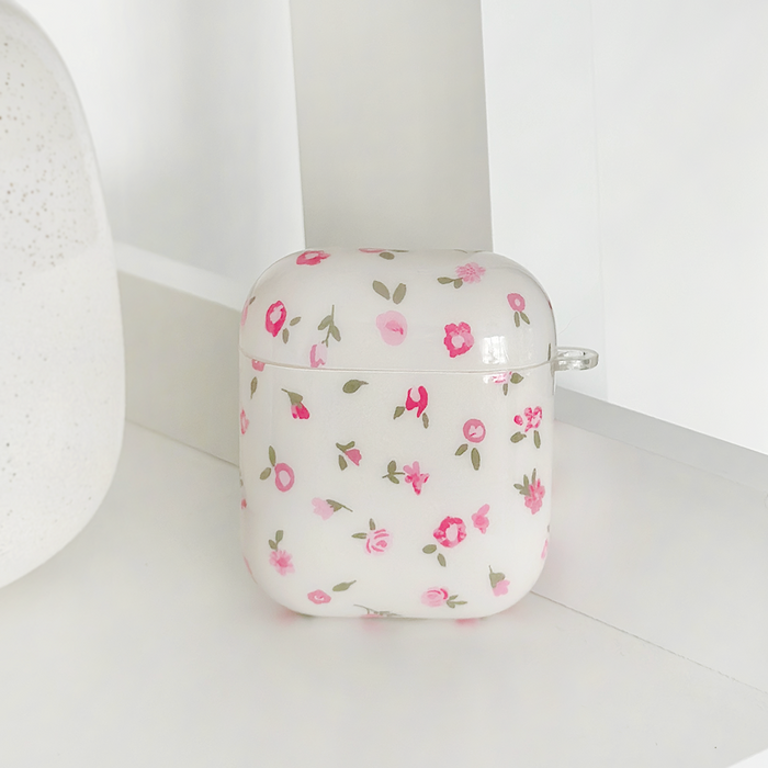 Pink watercolor floral Coconut Lane Airpods case on a white surface next to a light object.