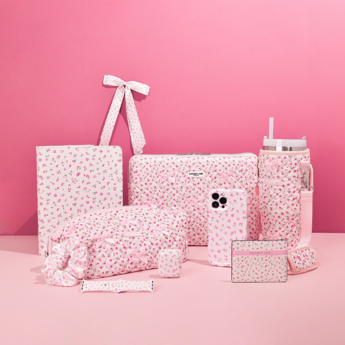 Pink AirPods case with watercolor flower design and matching pink floral accessories on a pink background.