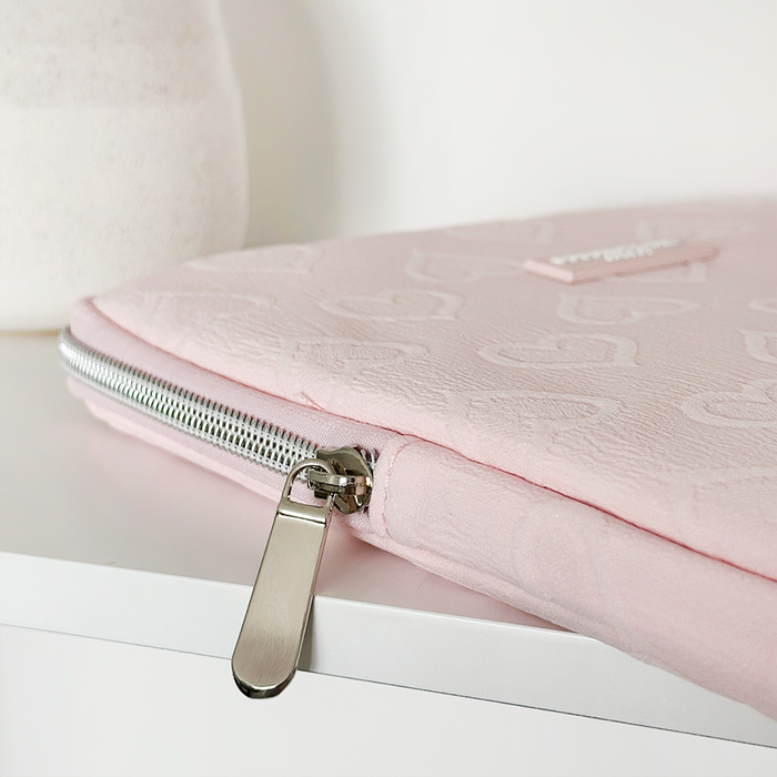 Baby pink heart-patterned iPad sleeve from Coconut Lane on a white surface beside a white vase.