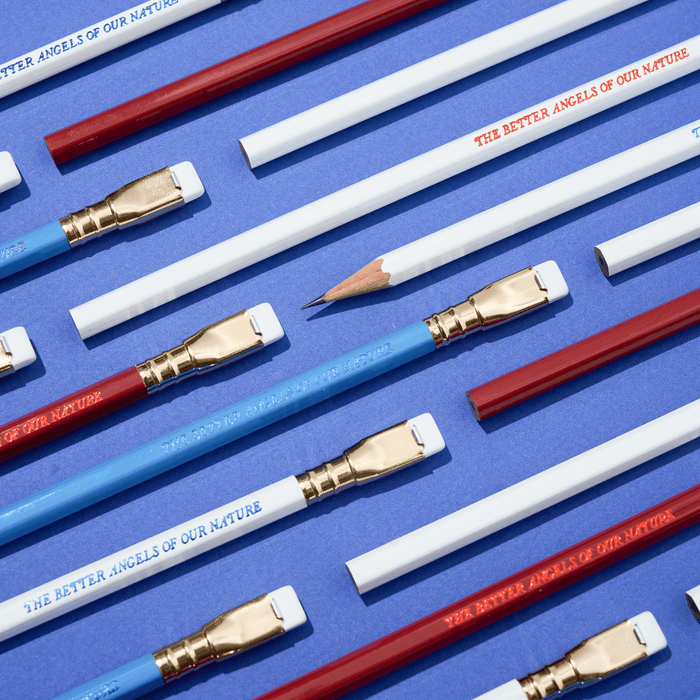 pencils that say 'THE BETTER ANGELS OF OUR NATURE' in red, white, and blue colorways arranged on a blue background