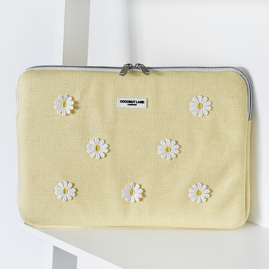 Coconut Lane Buttercup Bloom laptop sleeve with a white daisy pattern, displayed on a white shelf.