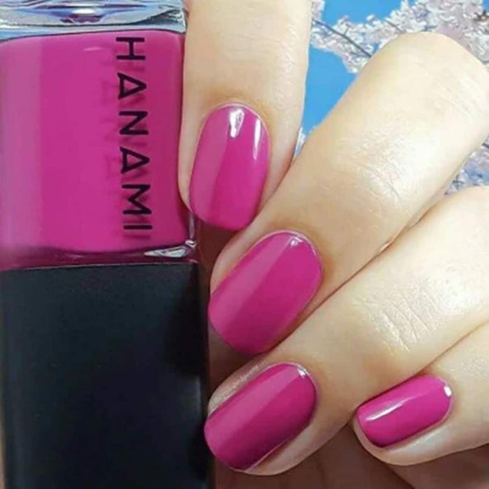 Hand with pink nails holding a bottle of Hanami nail polish.