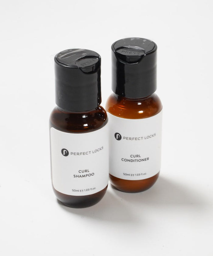 Two small bottles labeled Perfect Locks Curl Shampoo and Conditioner with black caps rest on a white surface, each holding 50ml.