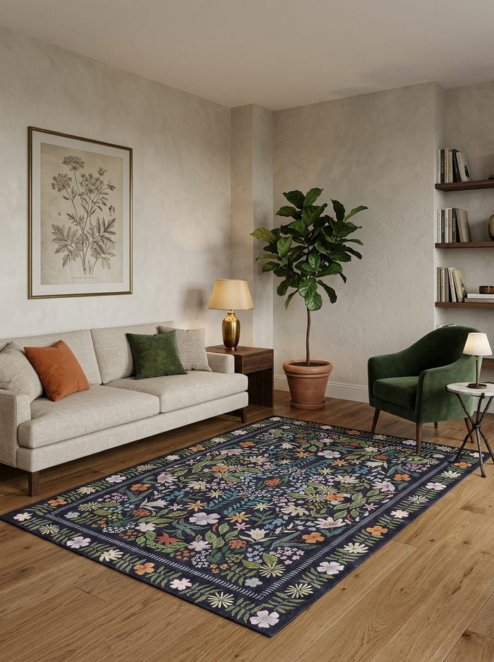 Dark navy rug with a colorful floral and botanical pattern, styled in a modern living room.