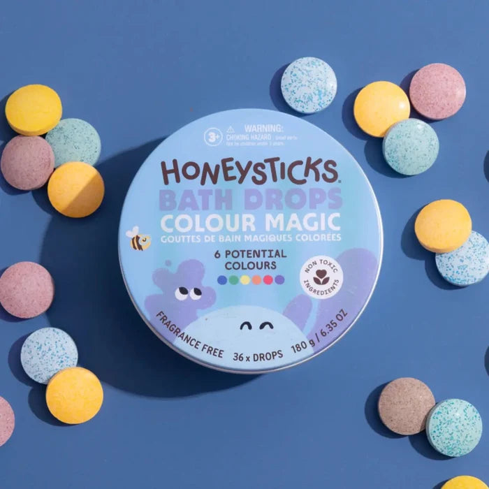 Honeysticks Bath Drops Colour Magic packaging with colorful bath bombs on a blue background