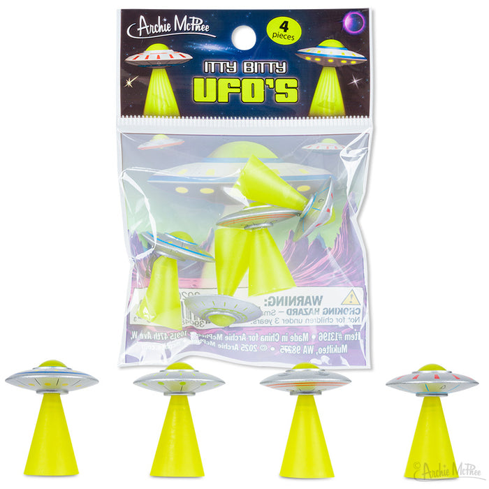 Four small soft vinyl UFOs, each with a green beam, displayed beneath a clear package labeled “Itty Bitty UFOs.”.