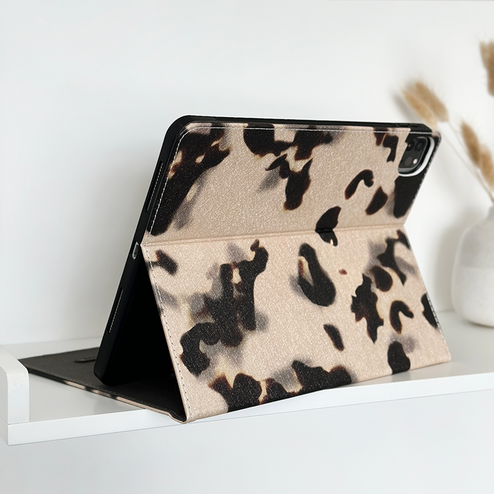 Tablet in Ivory Tort patterned Coconut Lane iPad case on white shelf next to a white vase with dried grass.