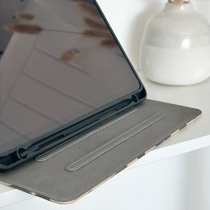 IPad in a cream tortoiseshell Coconut Lane case on a white table, pampas grass reflected on the screen.