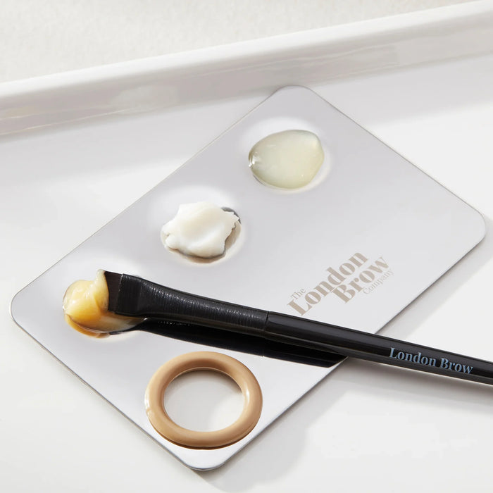 Makeup brush and products on a 'The London Brow' branded tray.