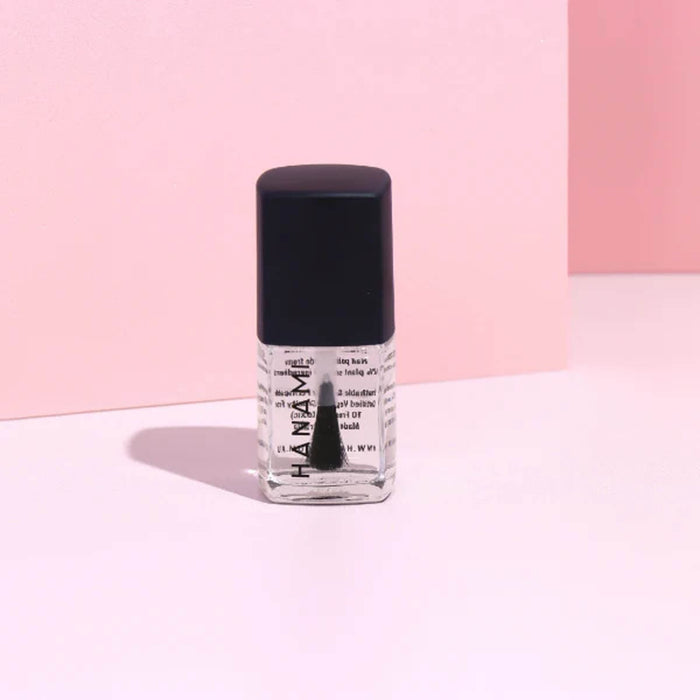 Bottle of nail polish with a black cap on a pink background.