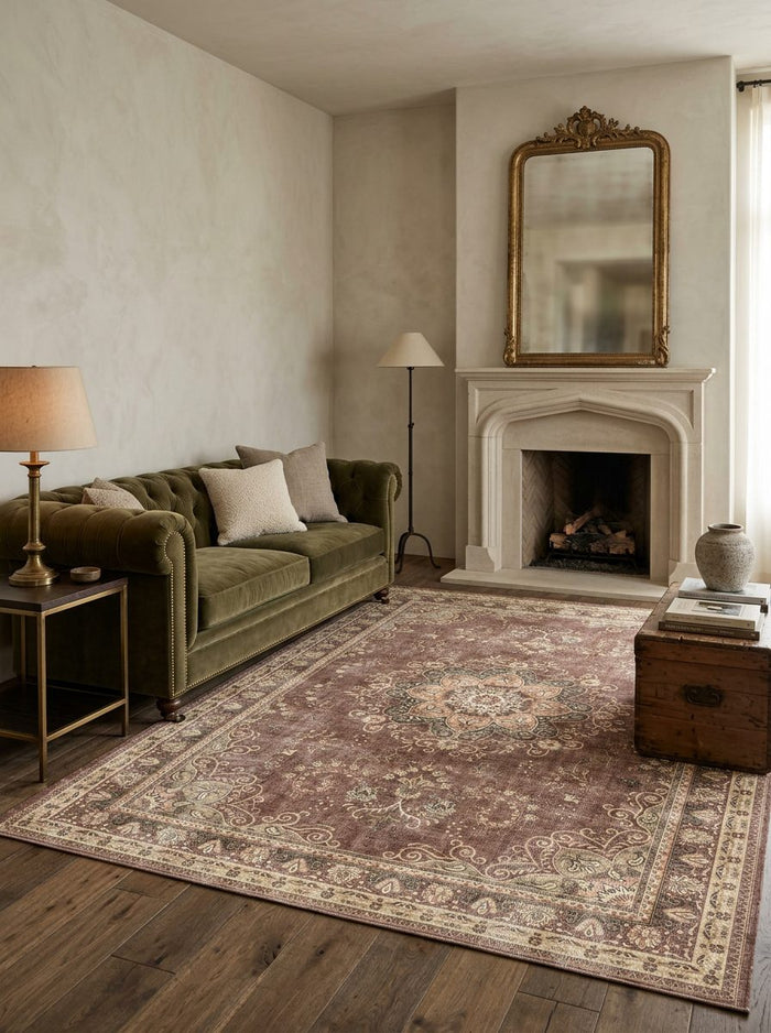 Distressed brown and cream traditional medallion rug in a living room with a green velvet sofa and fireplace.