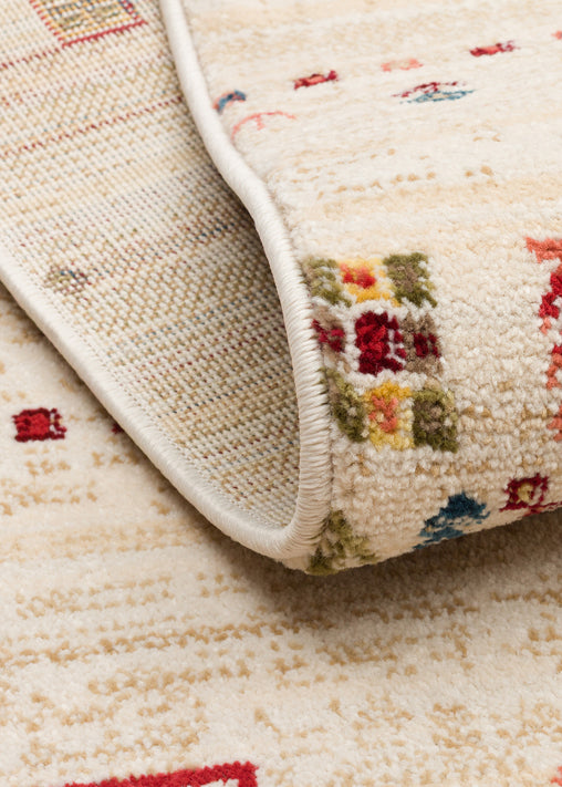 Cream rug with a folded corner revealing a multi-colored geometric pattern of red, blue, and green squares.
