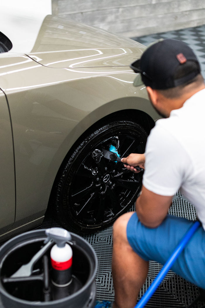 Person washing a car tire with a Detail Factory brush and KochChemie Multi Star.