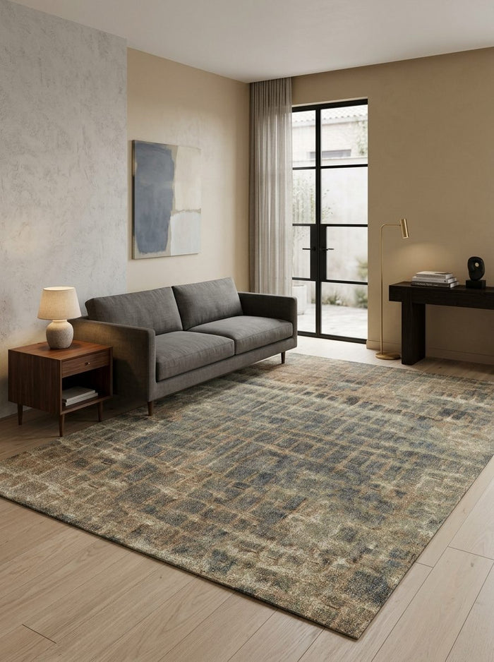 Distressed blue and brown grid-patterned rug in a modern living room with a grey sofa.