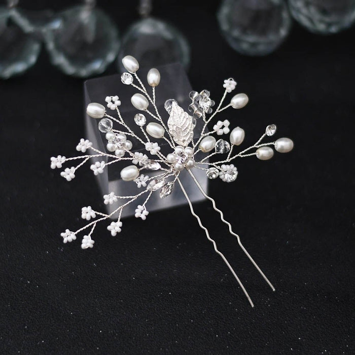 A decorative silver hairpin adorned with small white pearls, clear crystals, and delicate white flower accents in a branch-like design.