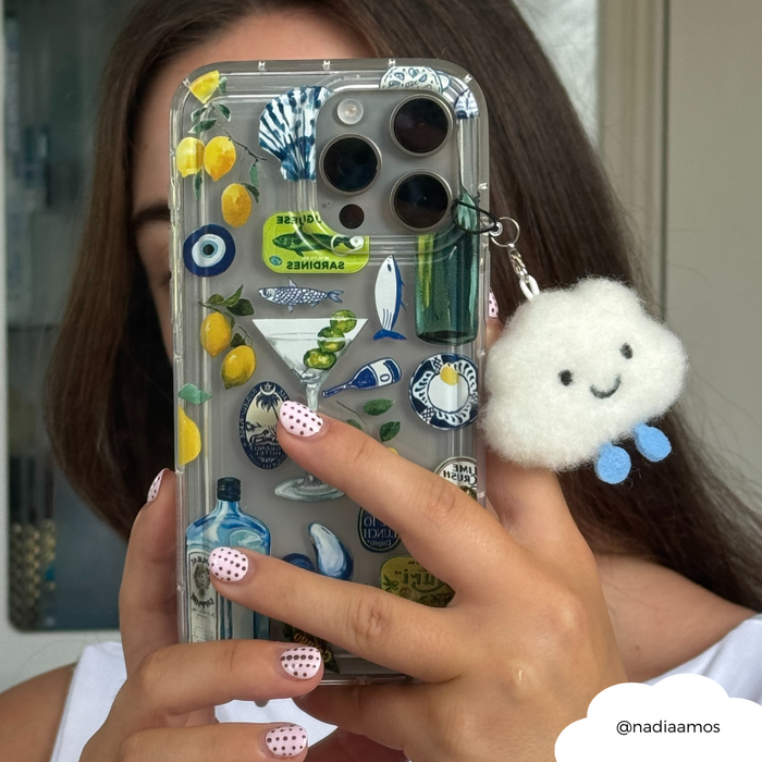 Hand with polka dot nails holding a phone decorated with stickers and a Coconut Lane Cloud phone charm; face hidden.