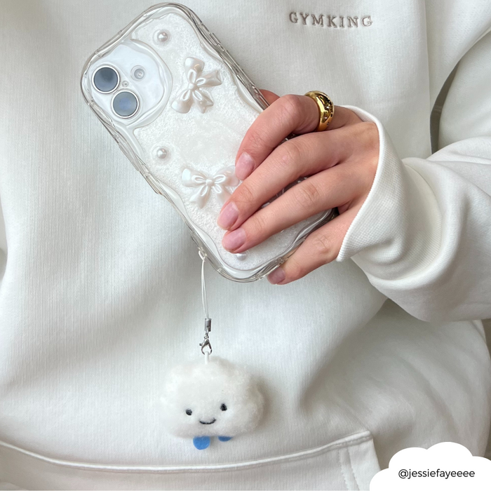 Clear phone case with bow accents and Coconut Lane Cloud Phone Charm, held by person in a white sweatshirt.