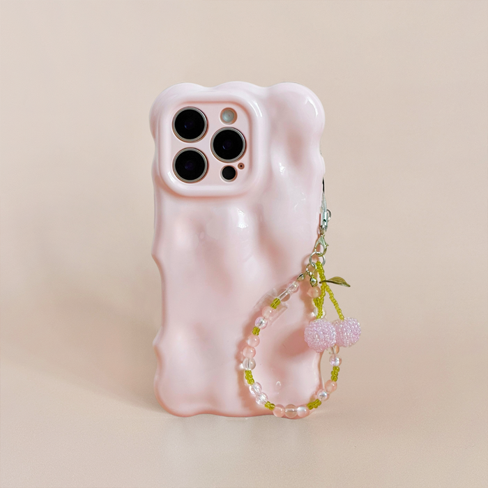 Pink cherry phone charm with green beads, paired with a pink wavy phone case on a beige background.