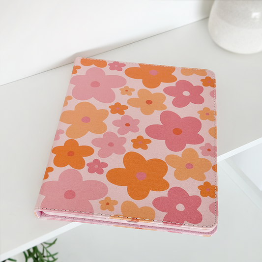 Pink and orange floral iPad case on a white shelf next to a white vase.