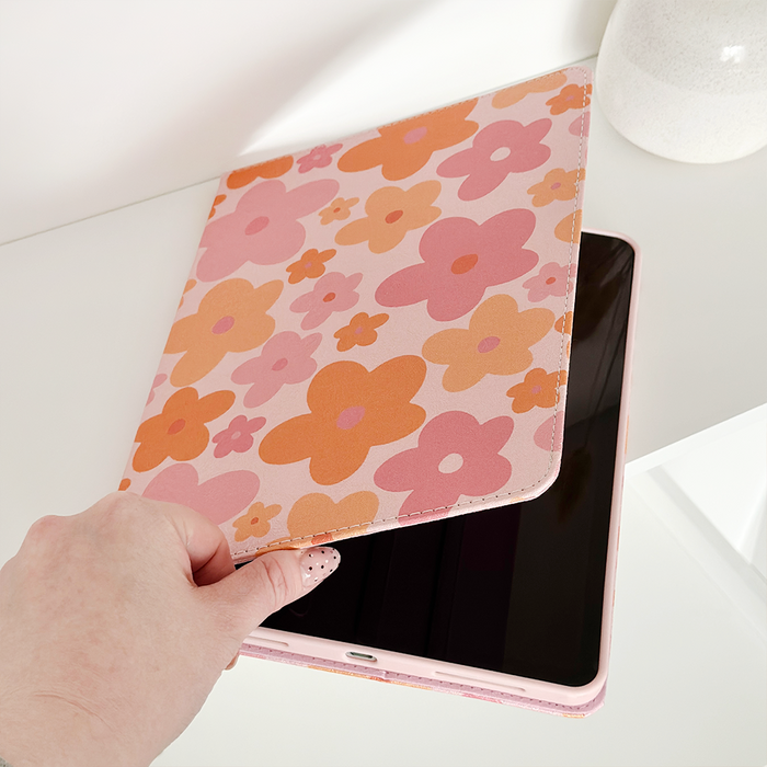 Hand opening a pink and orange floral Coconut Lane iPad case on a white surface.