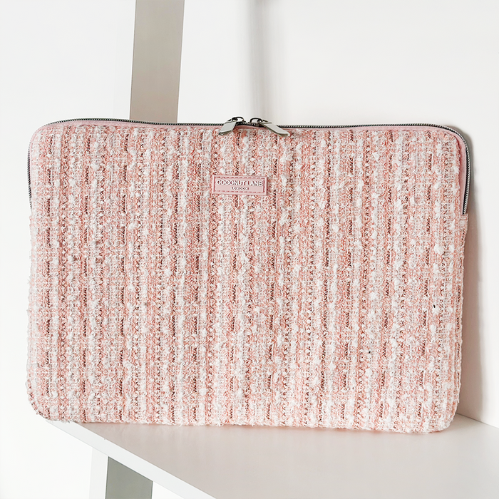 Pink textured tweed laptop sleeve with zipper, displayed upright on a white shelf.