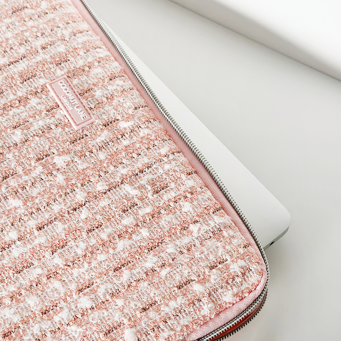 White laptop partially tucked into a pink textured tweed Coconut Lane laptop sleeve on a white surface.