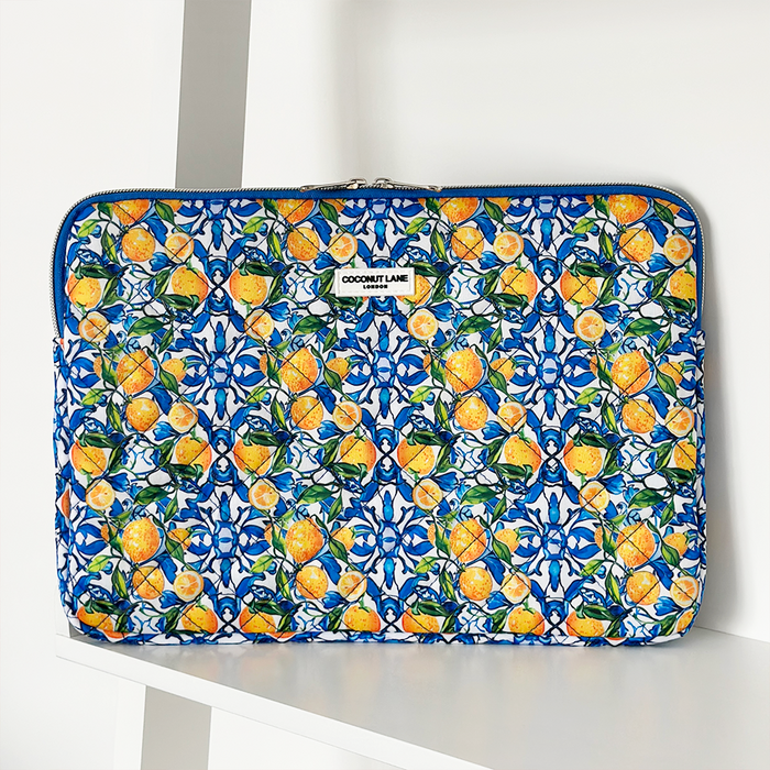 Quilted yellow lemon-patterned Coconut Lane laptop sleeve on a white shelf.