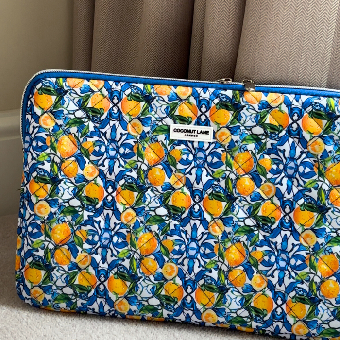 Quilted Coconut Lane laptop sleeve with a bright lemon citrus pattern, shown on a light carpet.