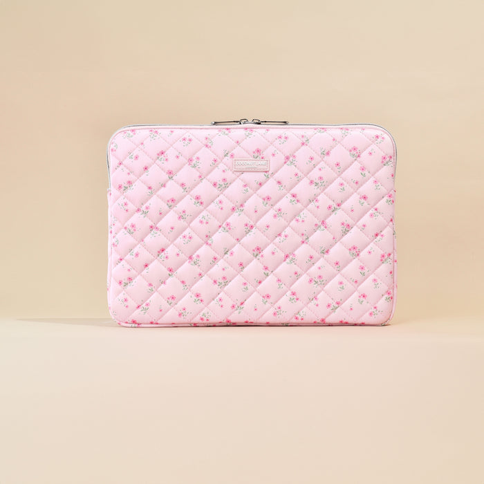 Pink quilted laptop sleeve with ditsy floral pattern on a beige background.