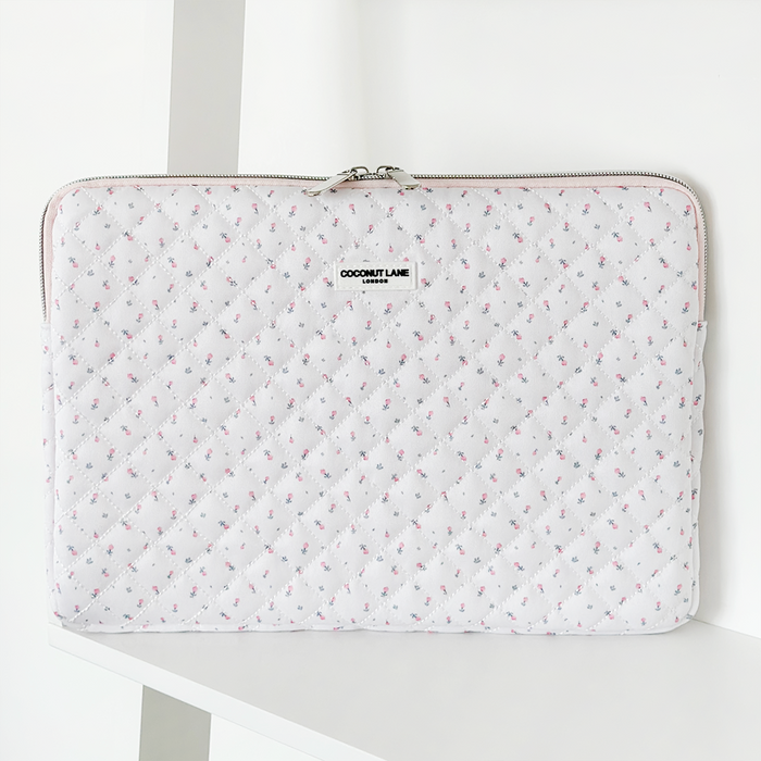 White quilted laptop sleeve with pink ditsy floral pattern and a zipper closure.