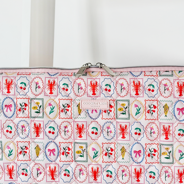 Quilted Coconut Lane laptop sleeve with a colorful stamp pattern, featuring lobsters, skulls, bows, olives, and fish.