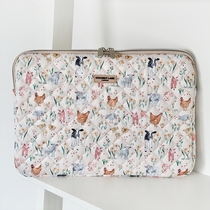 White quilted laptop sleeve with colorful cow, chicken, and pig illustrations from Coconut Lane.