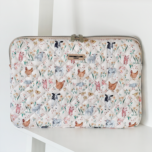 White quilted laptop sleeve with colorful cow, chicken, and pig illustrations from Coconut Lane.