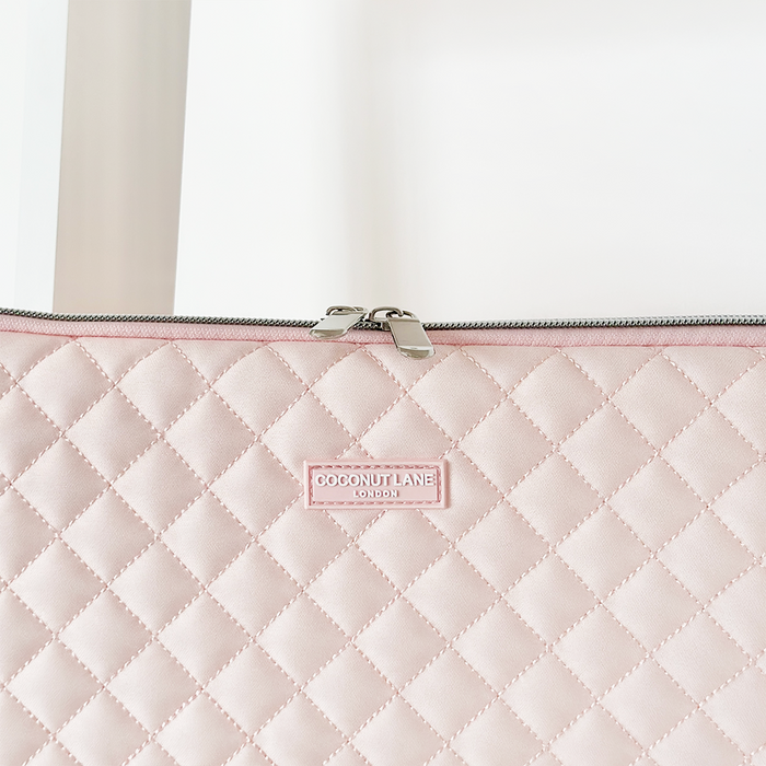 Quilted pink Coconut Lane laptop sleeve with zipper closure and a centered branded label.