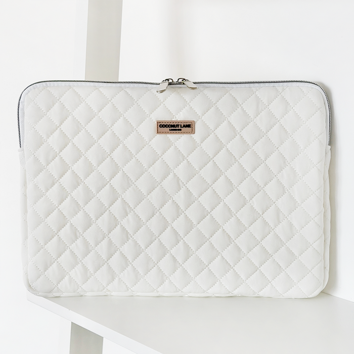 Quilted white laptop sleeve with coconut print, visible zipper, and a small Coconut Lane label on the front.