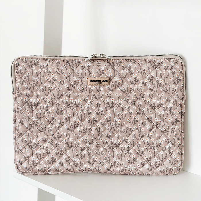 Coconut Lane nude floral quilted laptop sleeve on a white shelf.