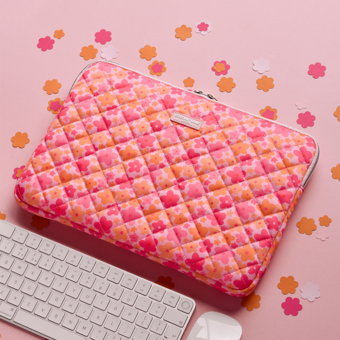 Pink and orange quilted laptop sleeve by Coconut Lane beside a white keyboard on a pink surface with confetti.